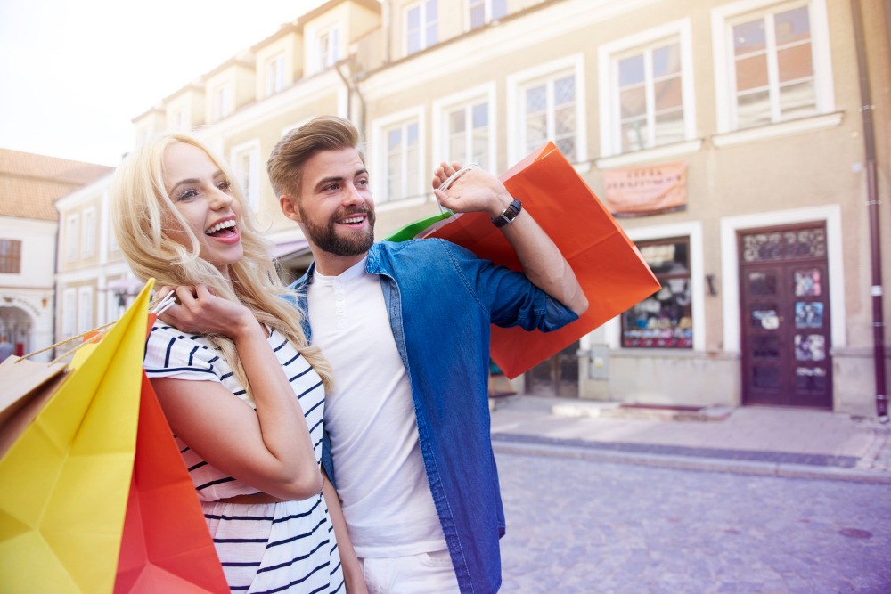 Mladý pár si užívá podzimní nákupy během akce Ona Dnes a odnáší si tašky s výhodnými slevami.