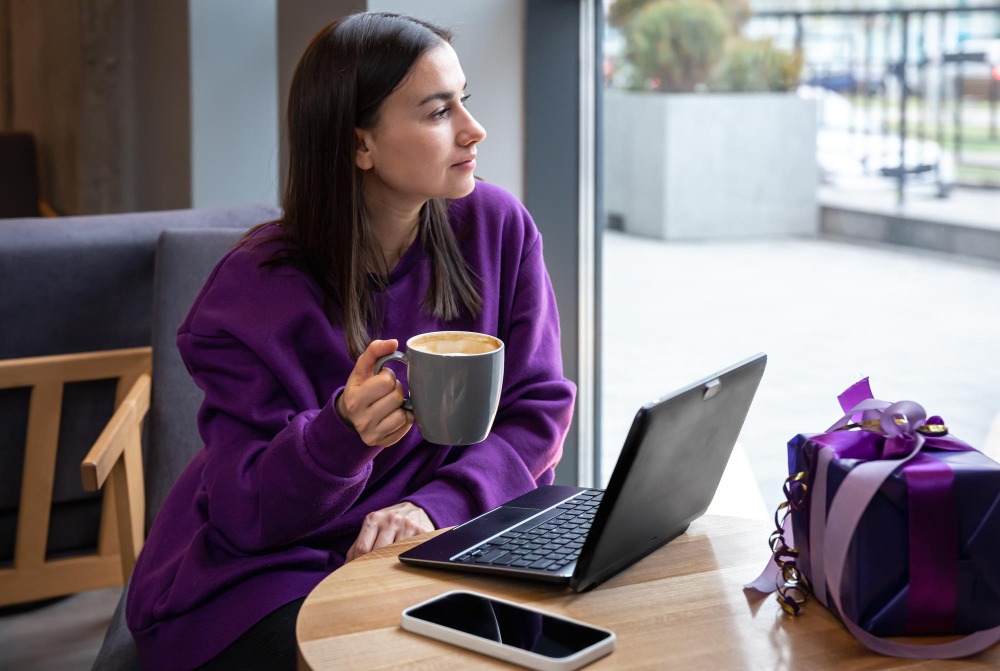 Žena u notebooku sleduje slevové kódy Ona Dnes 2025 na webu Promokupon.cz při kávě v kavárně
